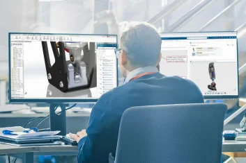 Engineer reviewing 3D CAD model on dual monitors
